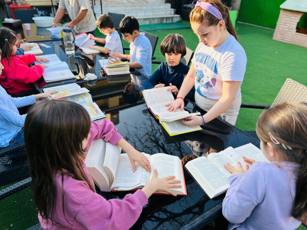 Copii la YuHuu Learning, la masă, lucrând la teme cu cărțile deschise